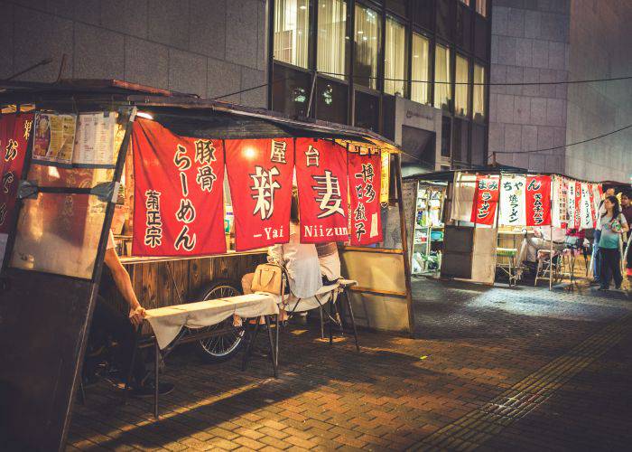 A street in Fukuoka with people setting up yatai food stalls.